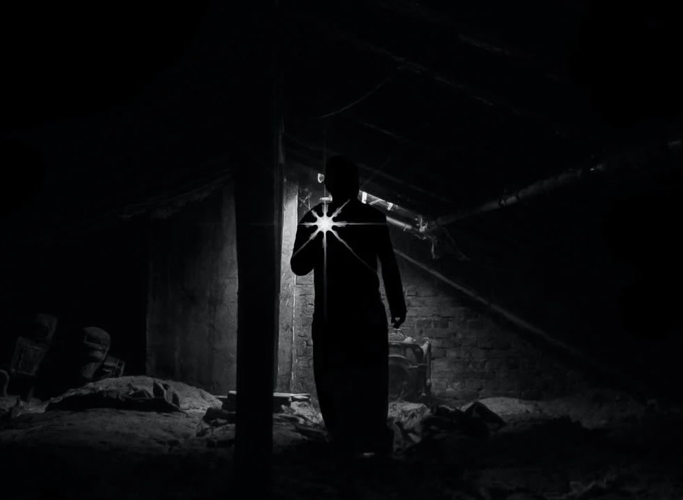 black and white image of eerie shadows and someone standing with a flashlight with curiousity